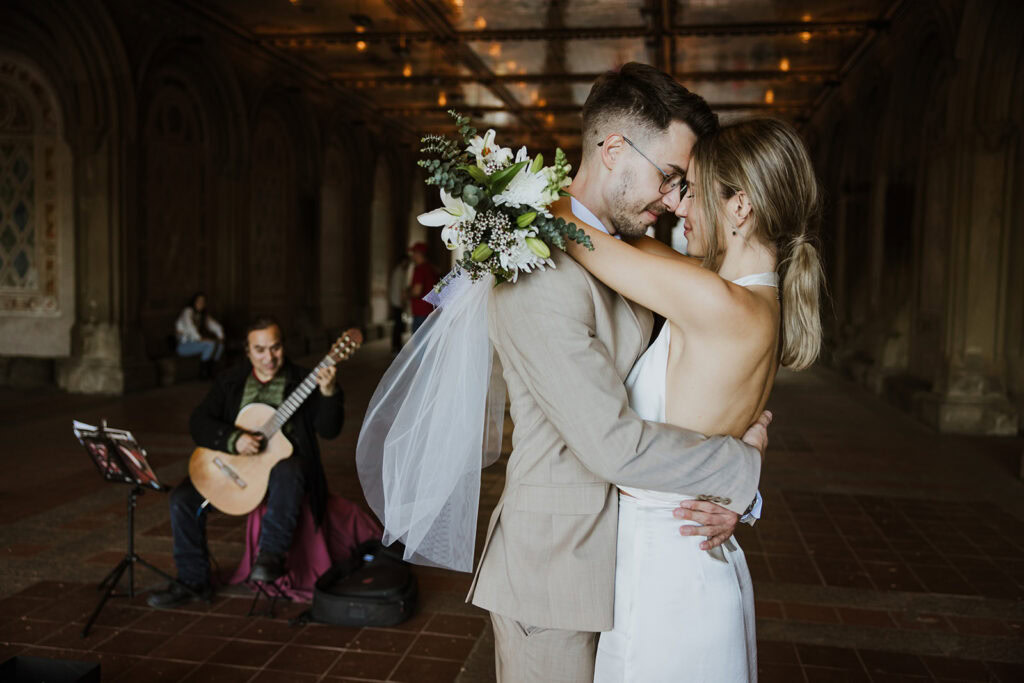 Newlywed couple enjoys first dance while they are serenaded by a live musician at Central Park elopement.