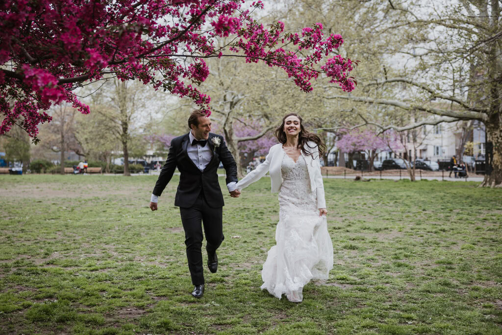 Couple runs through Central Park surrounded by spring redbud blooms after their NYC elopement.