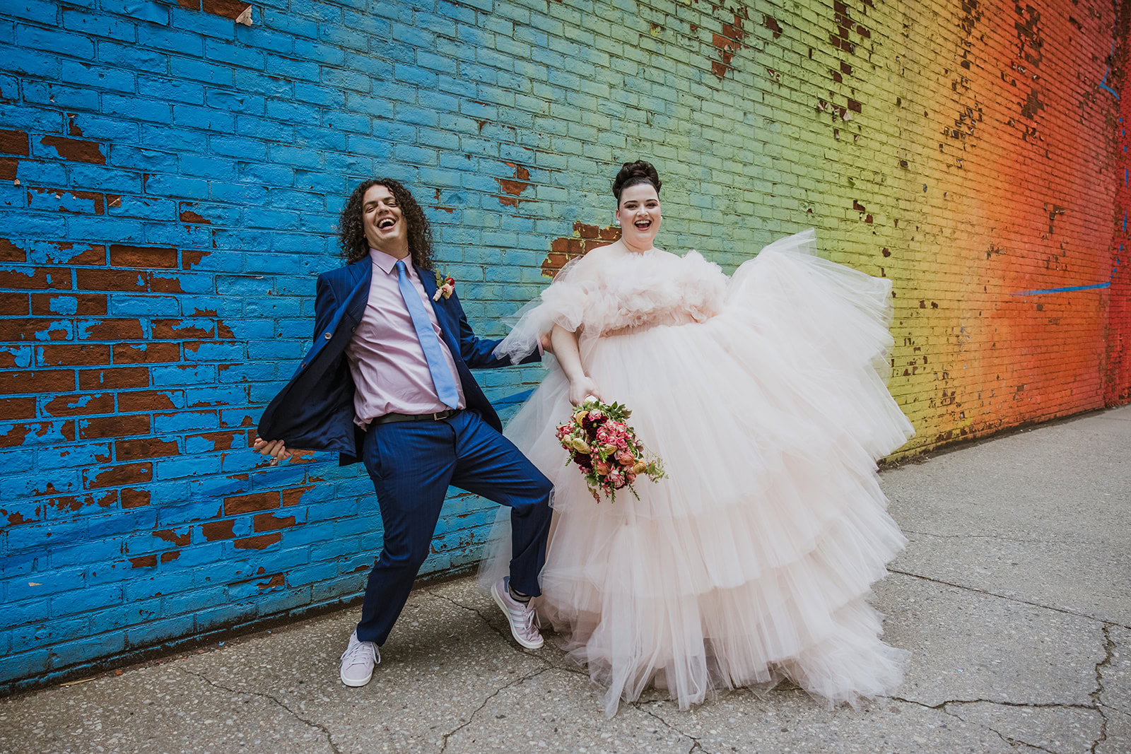 Happy couple elopes in NYC, taking photos in front of street art.